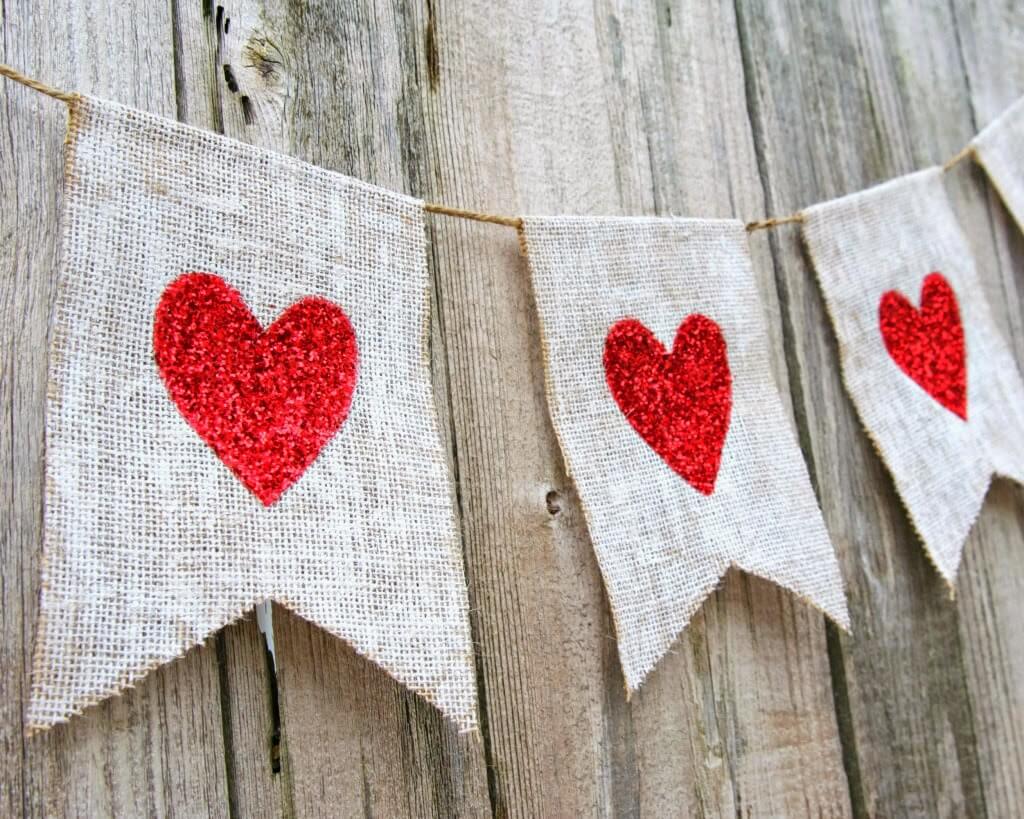 A burlap banner with red hearts on it
