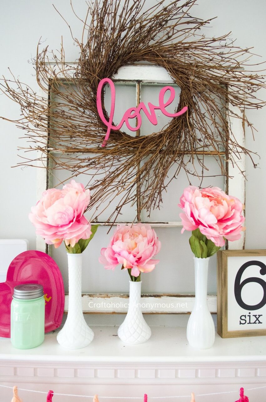 Pink flowers are in vases on a mantle
