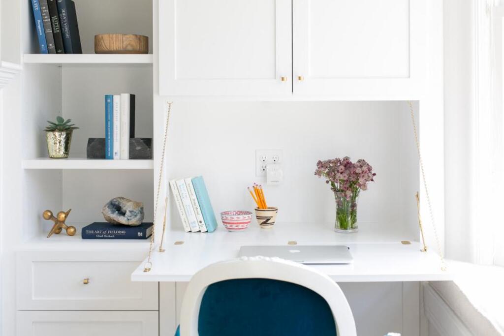 A white desk with a blue chair in front of it
