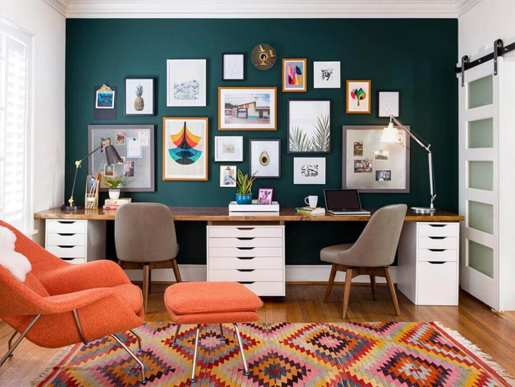 A room with a desk, chairs and pictures on the wall
