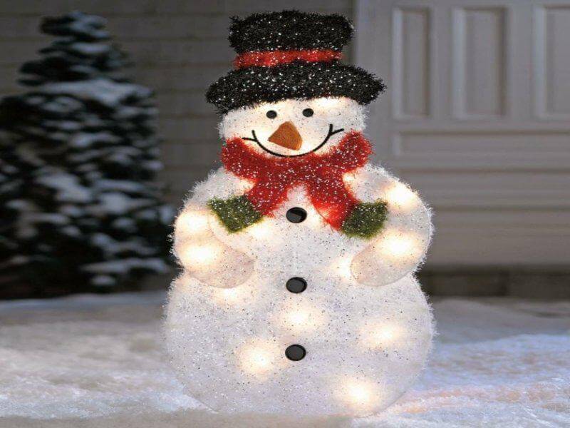 A lighted snowman standing in the snow
