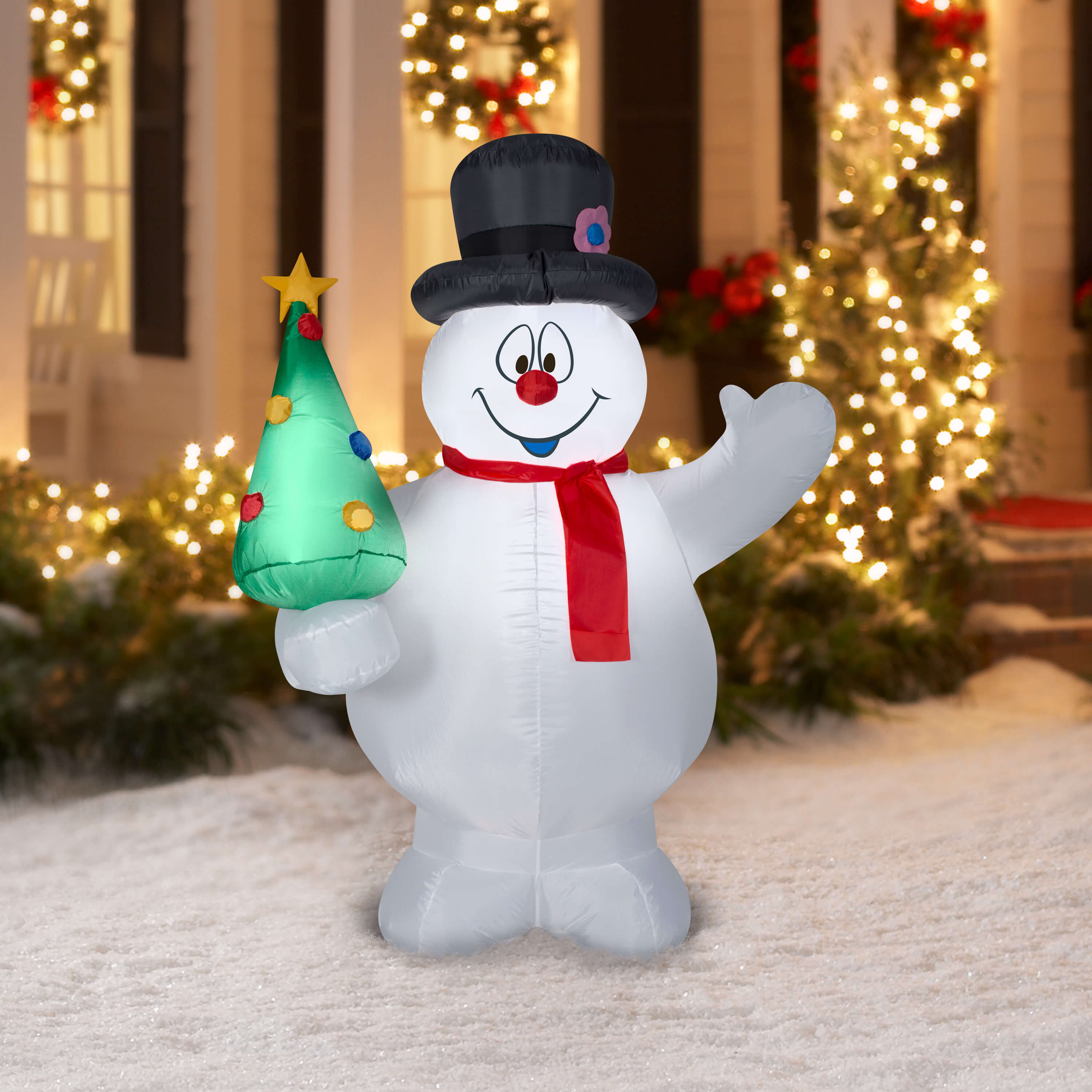 A large inflatable snowman holding a christmas tree
