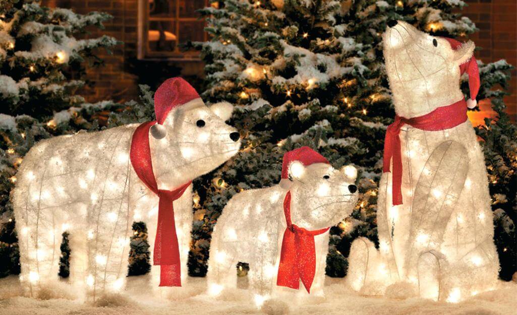 A couple of polar bears standing next to a christmas tree
