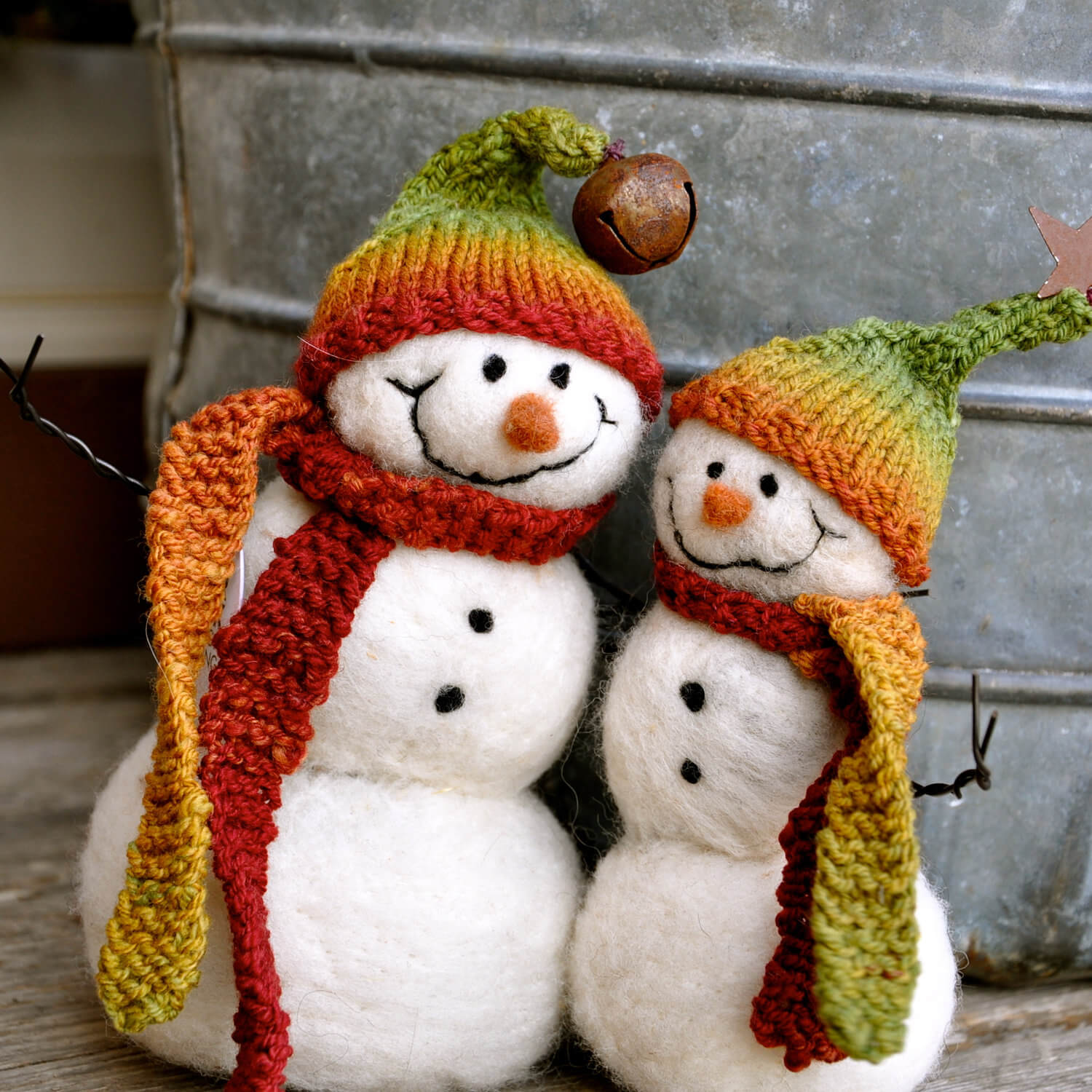 A group of three snowmen wearing hats and scarves
