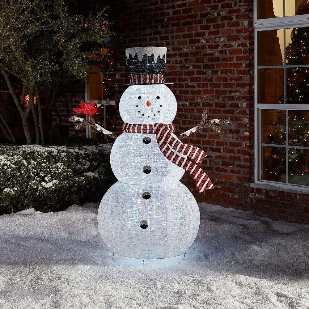 A snowman made out of plastic bottles in front of a house
