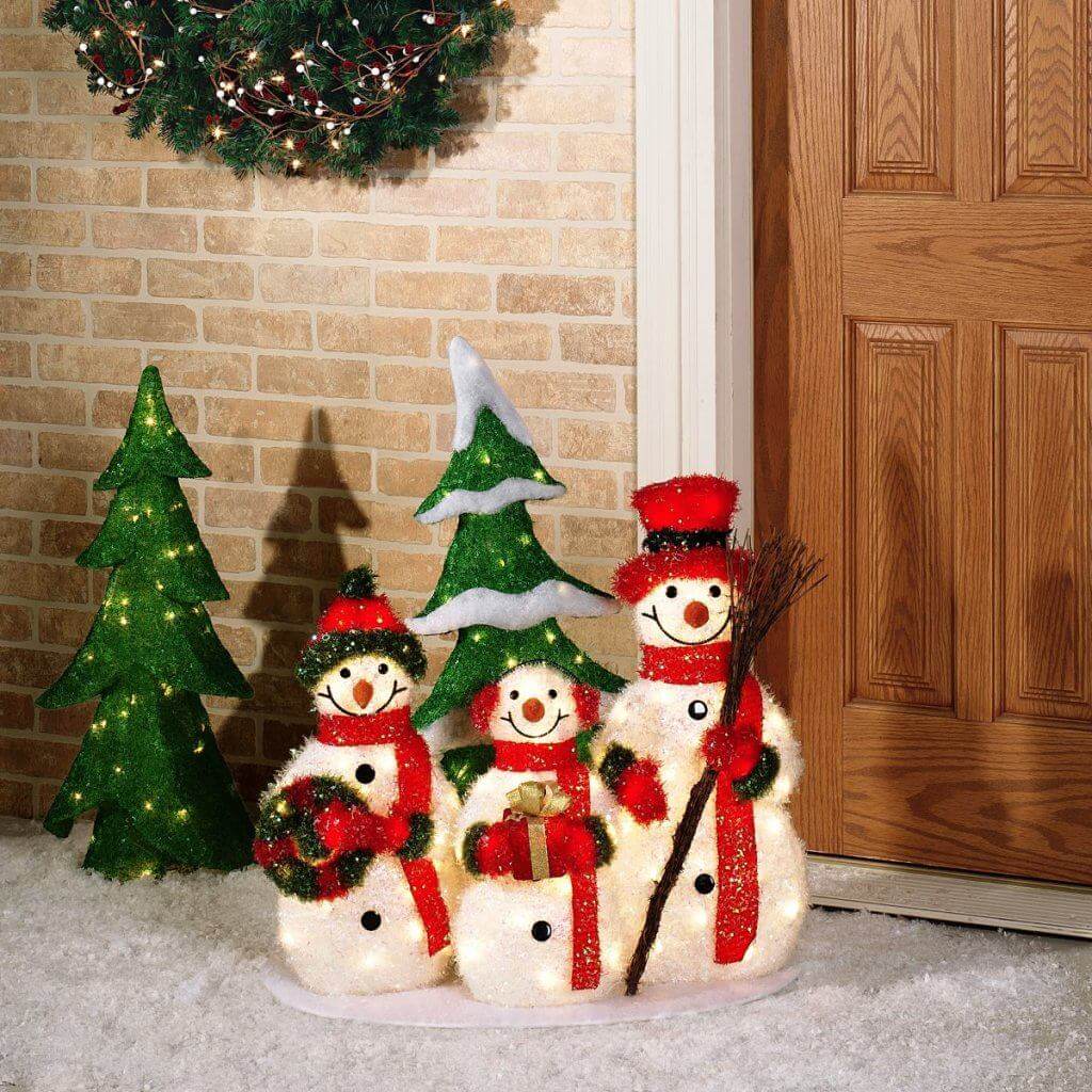 A group of snowmen standing next to a christmas tree
