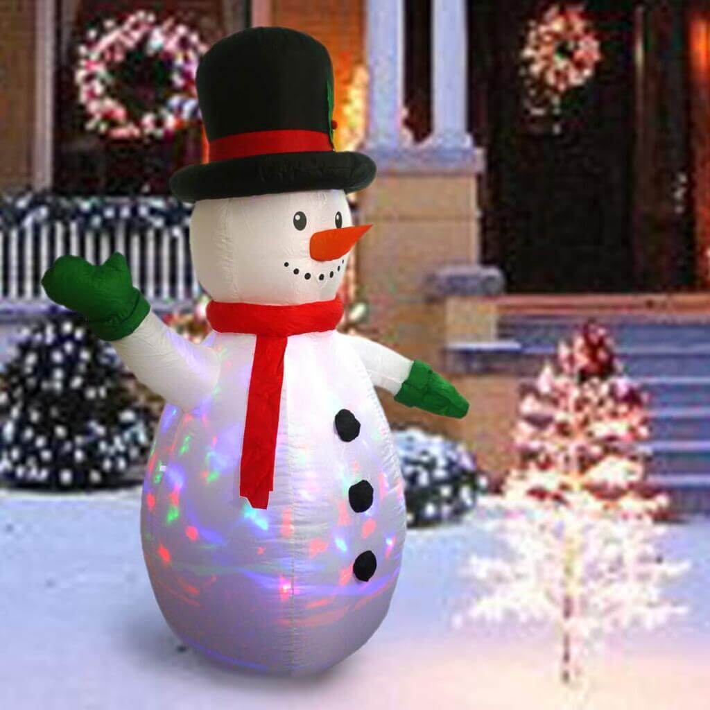 A snowman is standing in front of a house
