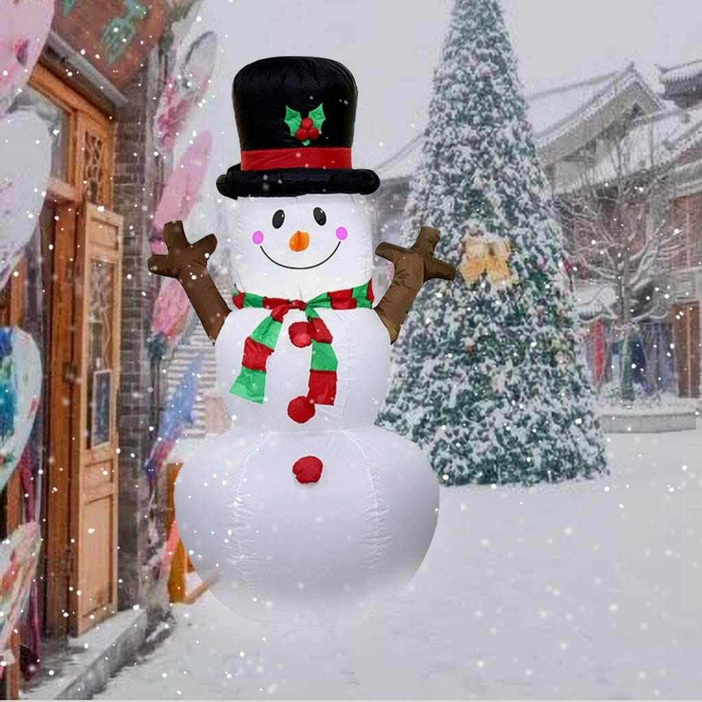 A snowman with a top hat and scarf standing in front of a christmas tree
