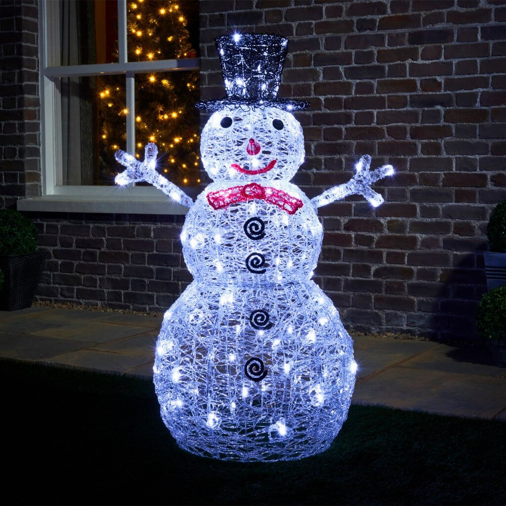 A lighted snowman in front of a house
