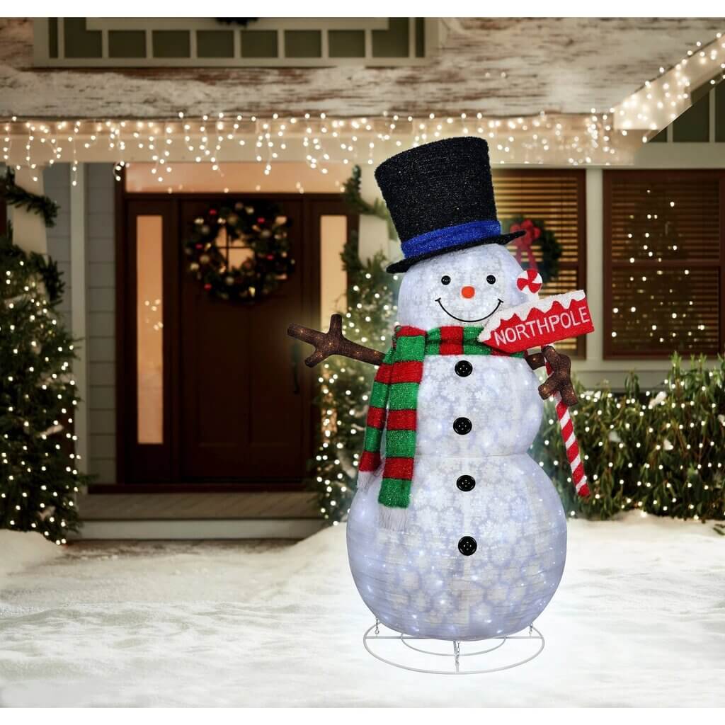 A snowman is standing in front of a house
