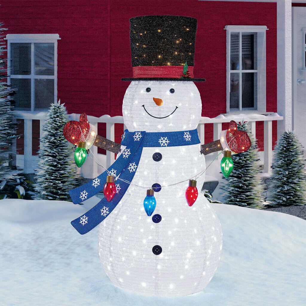 A lighted snowman in front of a red house
