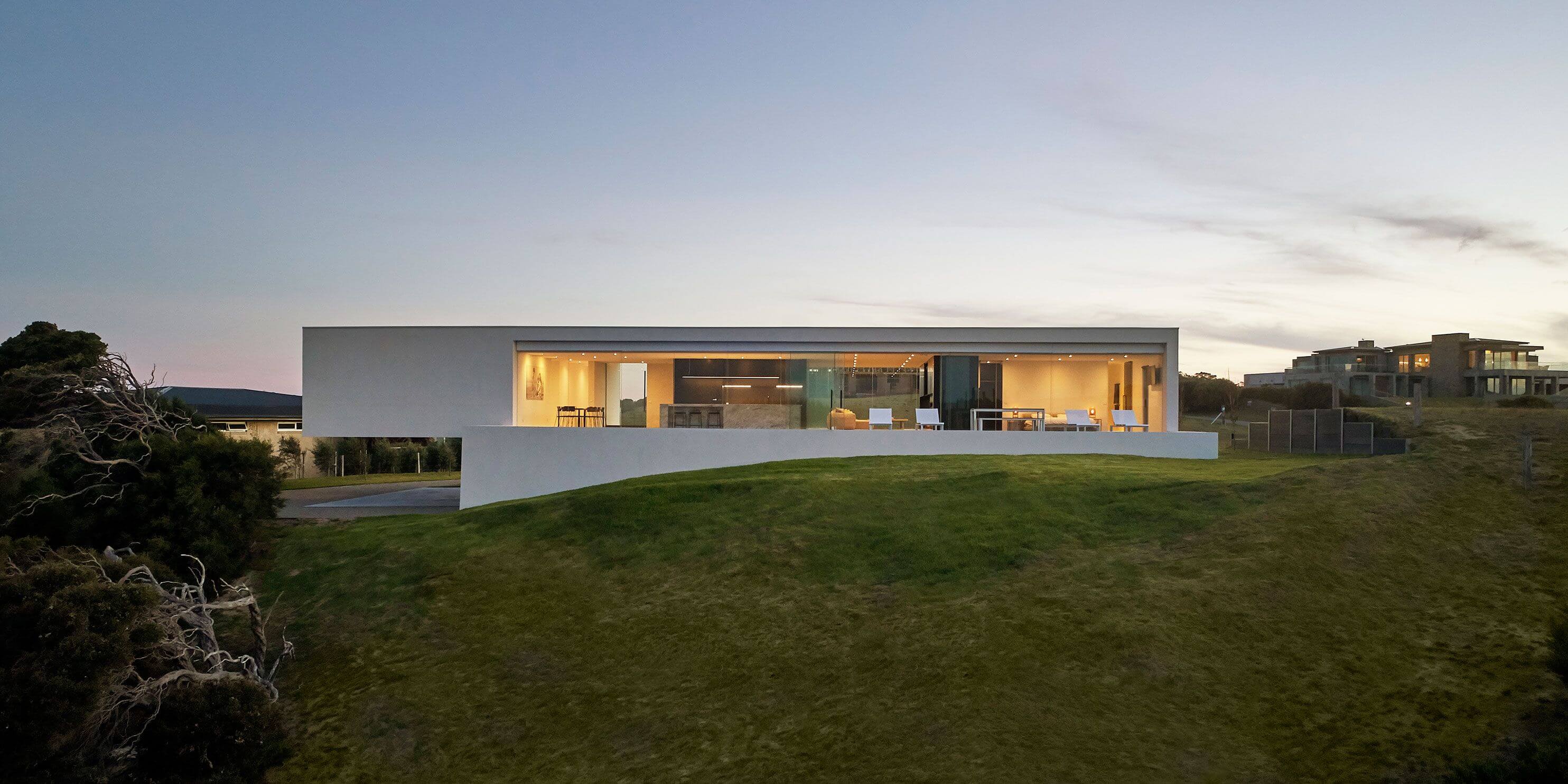A modern house on a hill overlooking the ocean
