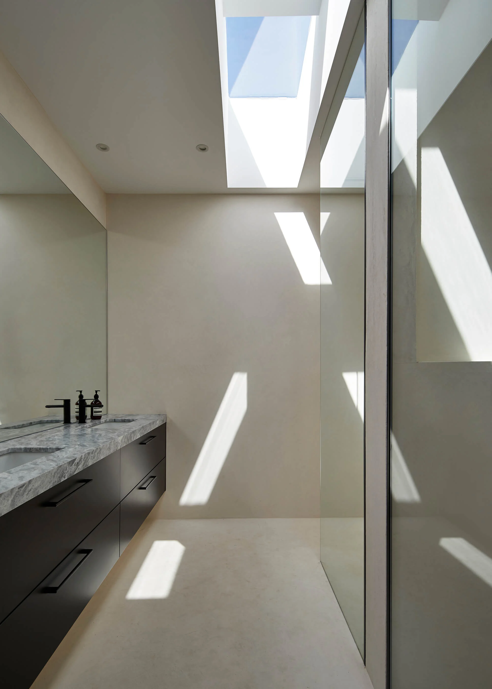 A bathroom with a double vanity and a skylight

