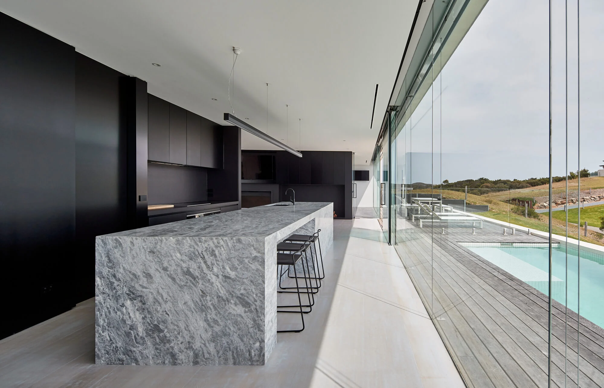 A kitchen with a marble counter top next to a swimming pool
