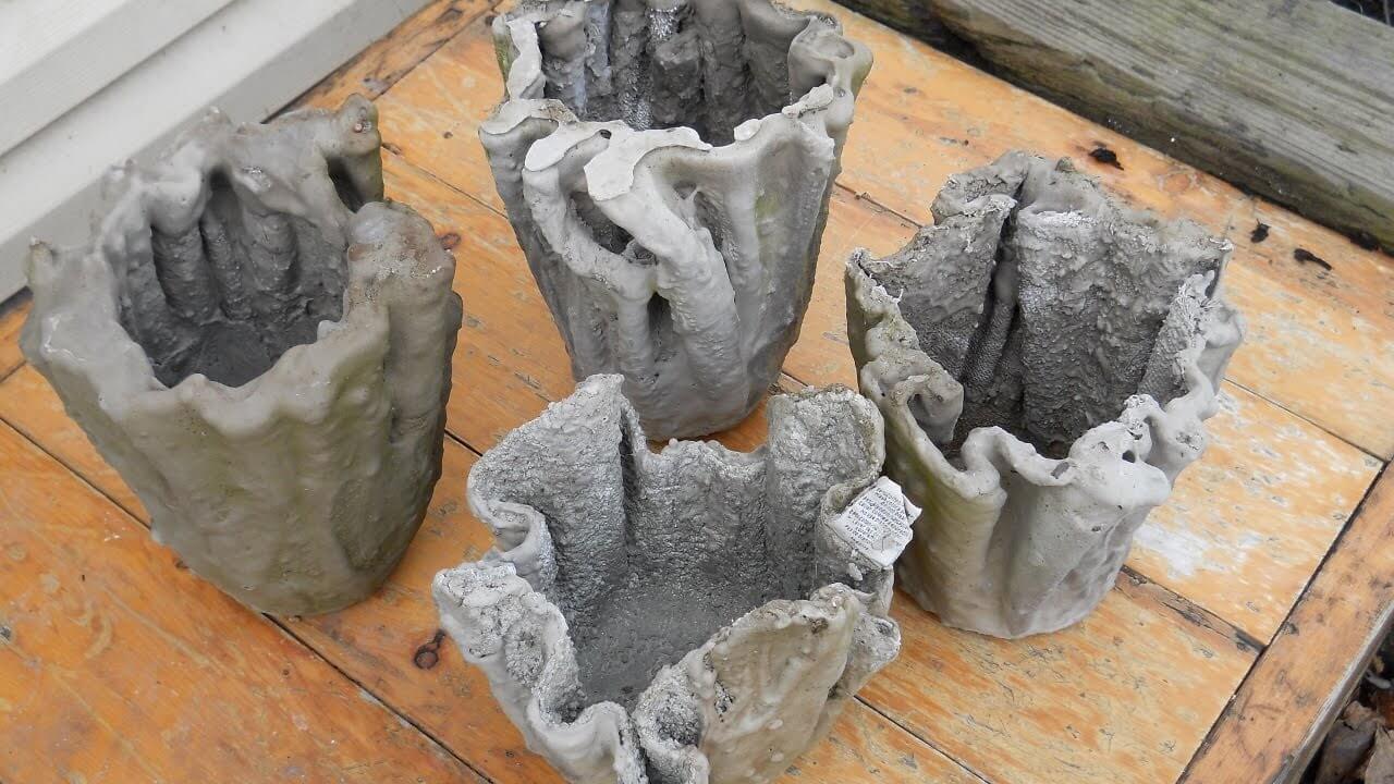 Three cement pots sitting on top of a wooden table
