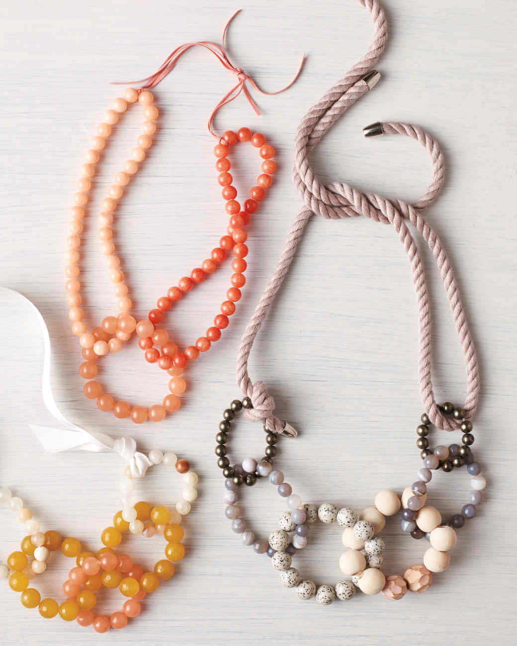 Three necklaces of different colors and shapes on a white surface
