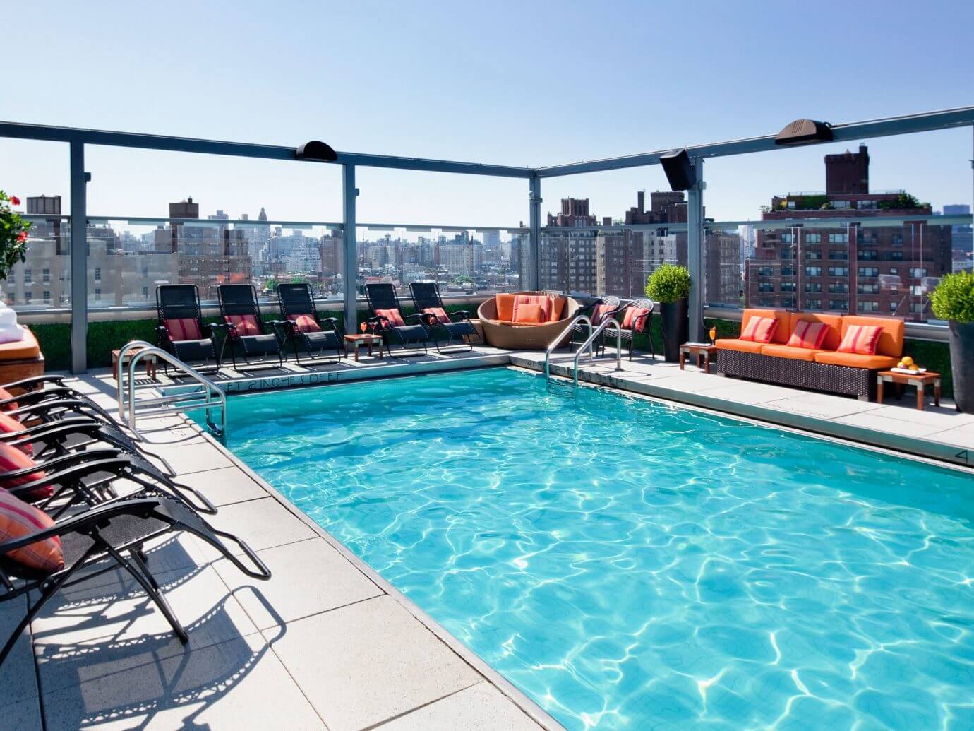 A swimming pool with lounge chairs and a view of the city
