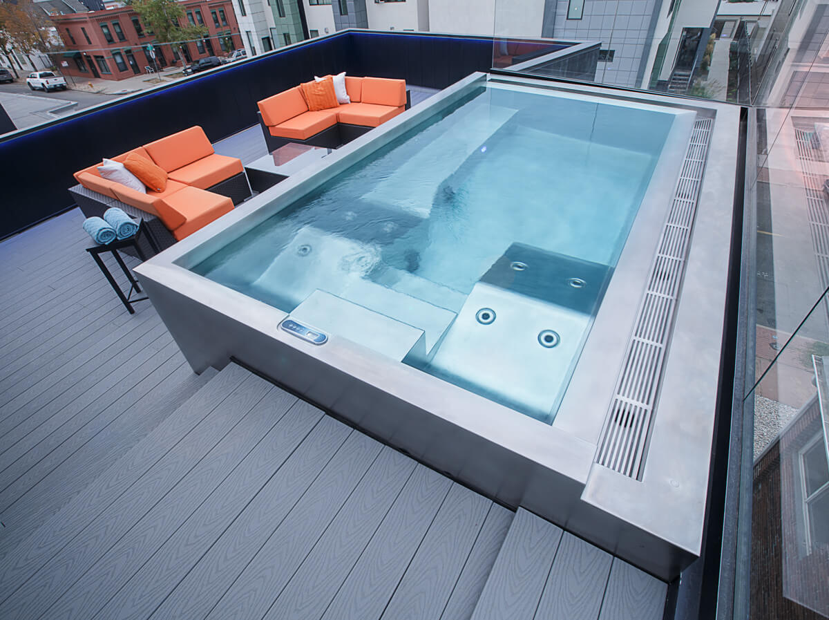 A hot tub on a deck with orange chairs
