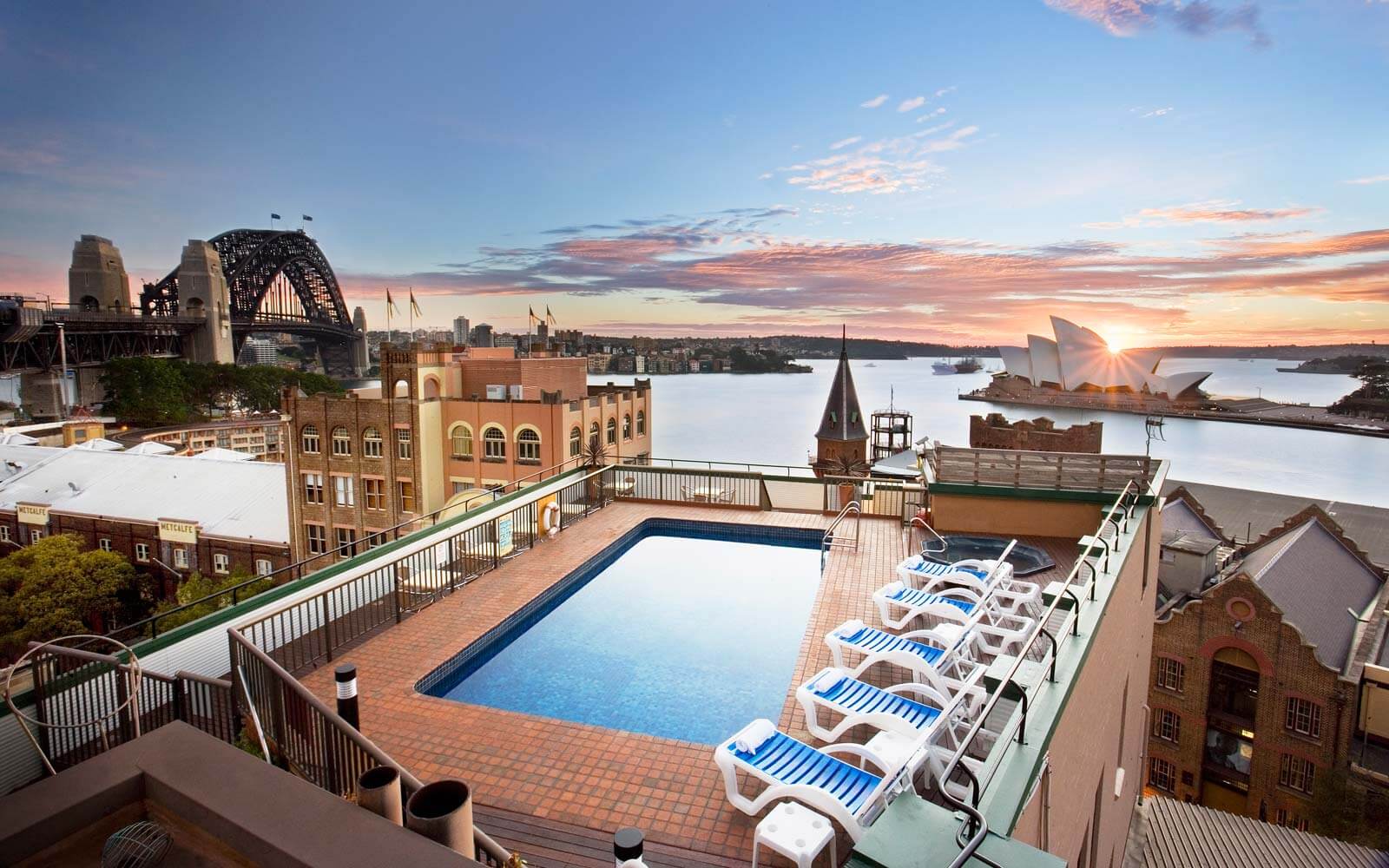 An outdoor swimming pool with lounge chairs and a view of the sydney harbour
