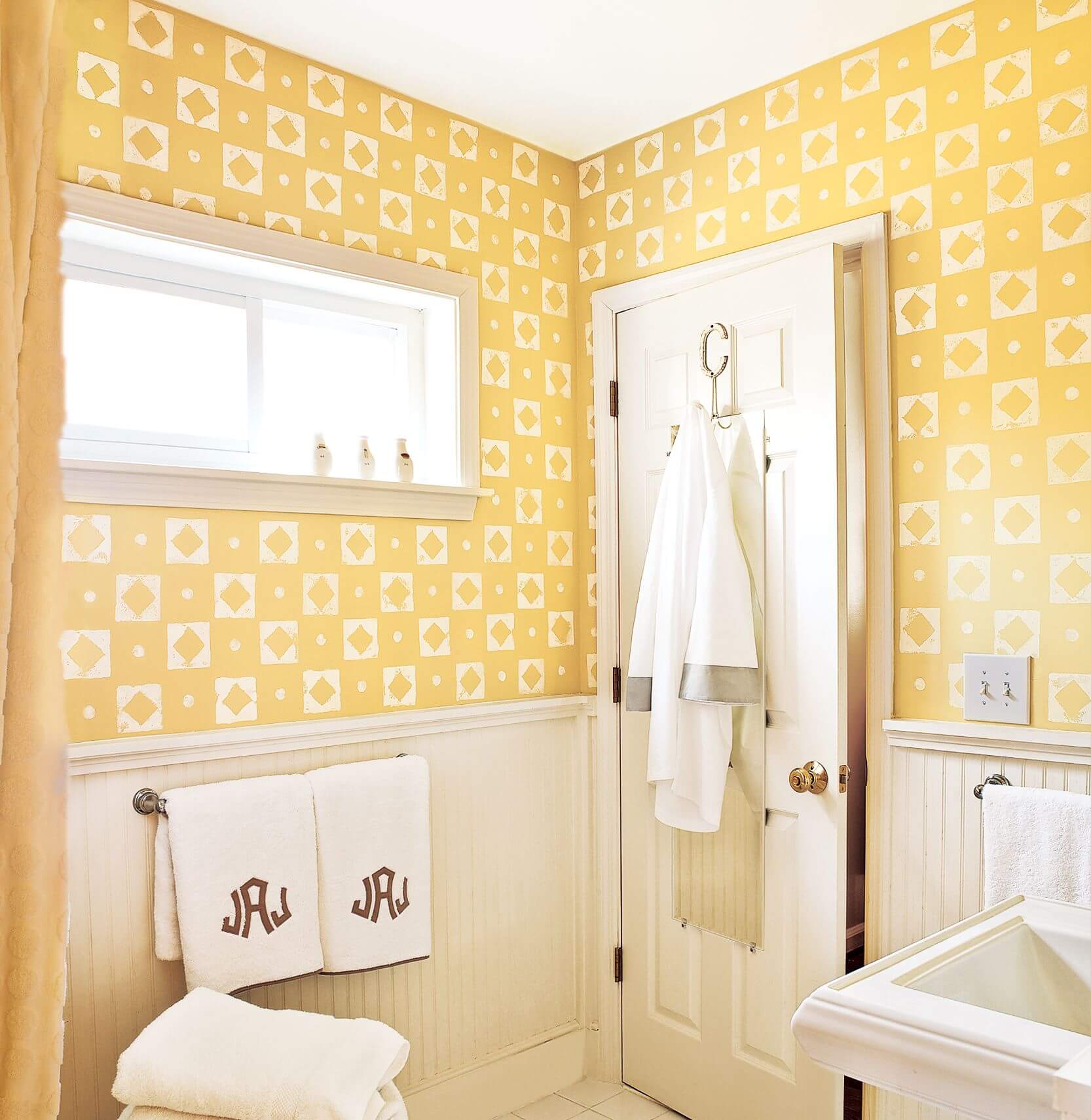 A bathroom with yellow and white wallpaper and towels
