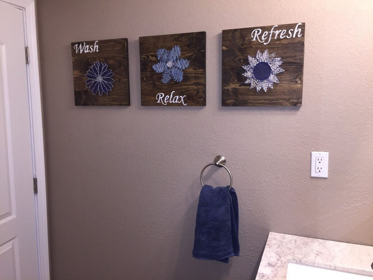 A bathroom with a towel rack and three pictures on the wall
