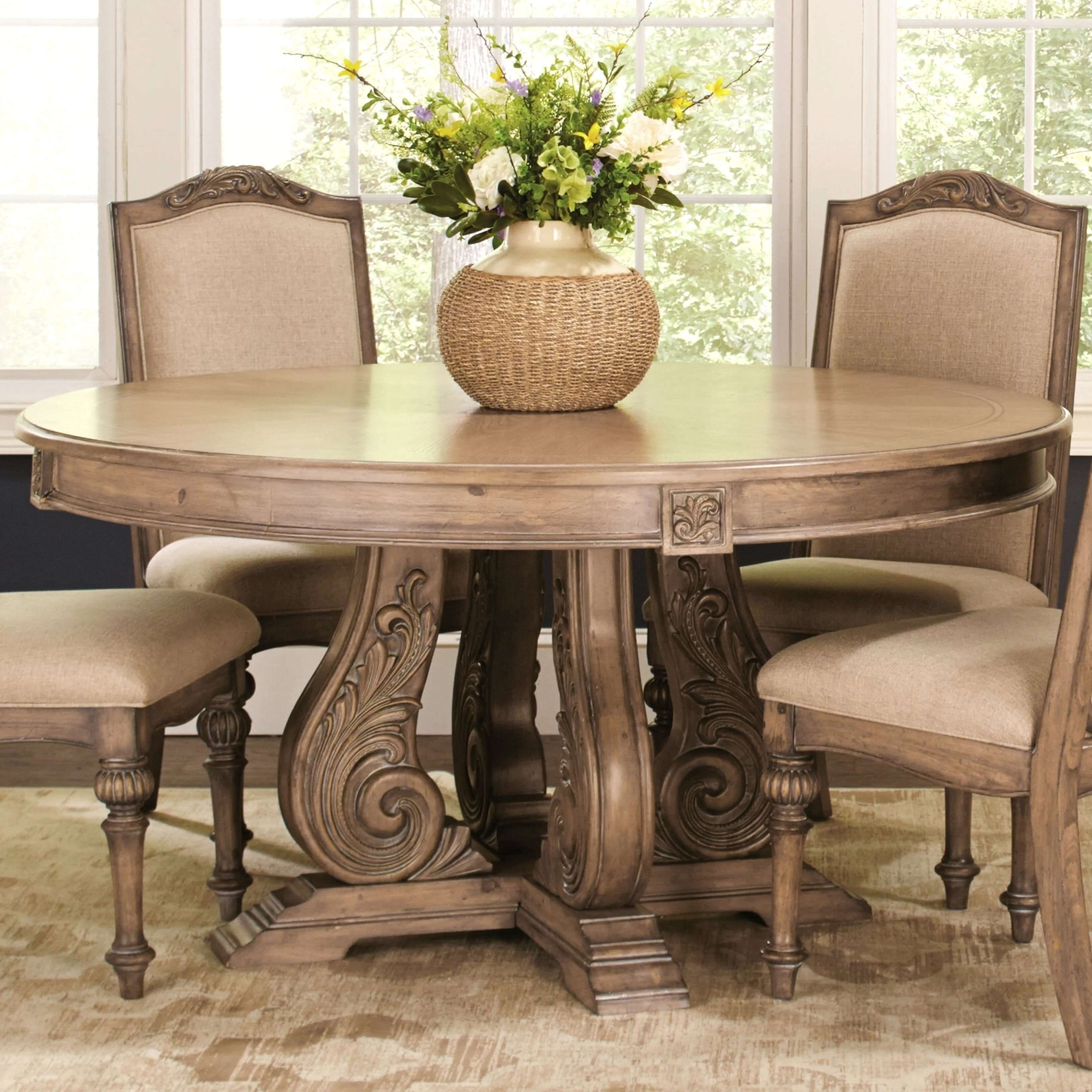 A round dining room table with a vase of flowers on top of it
