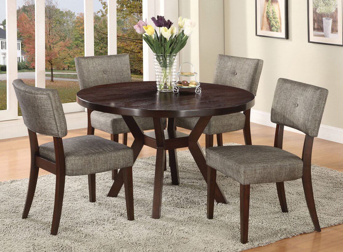 A round dining room table with a vase of flowers on top of it
