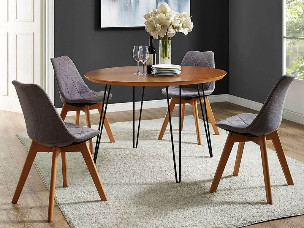 A round dining room table with chairs and a vase of flowers
