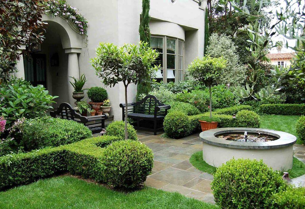 A garden with a fountain in the middle of it
