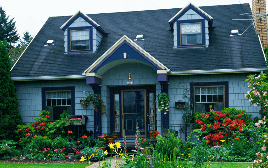 A blue house with flowers in front of it
