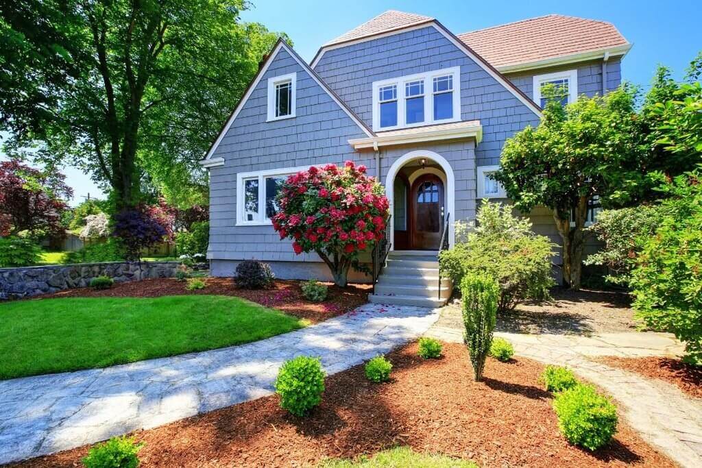 A house with a driveway and landscaping in front of it
