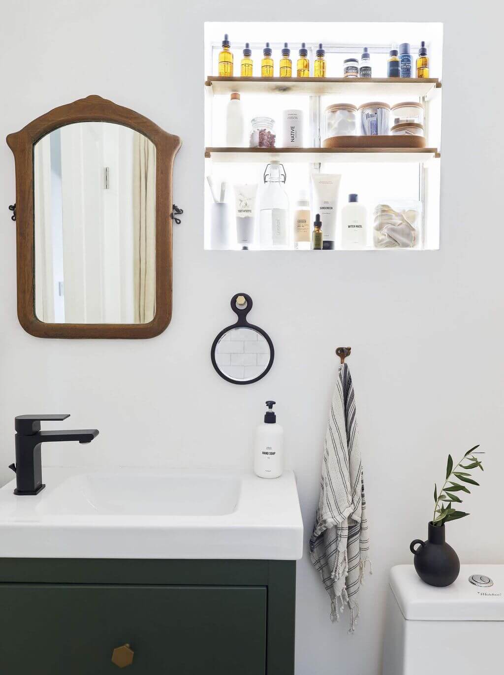 A bathroom with a sink, mirror and shelves
