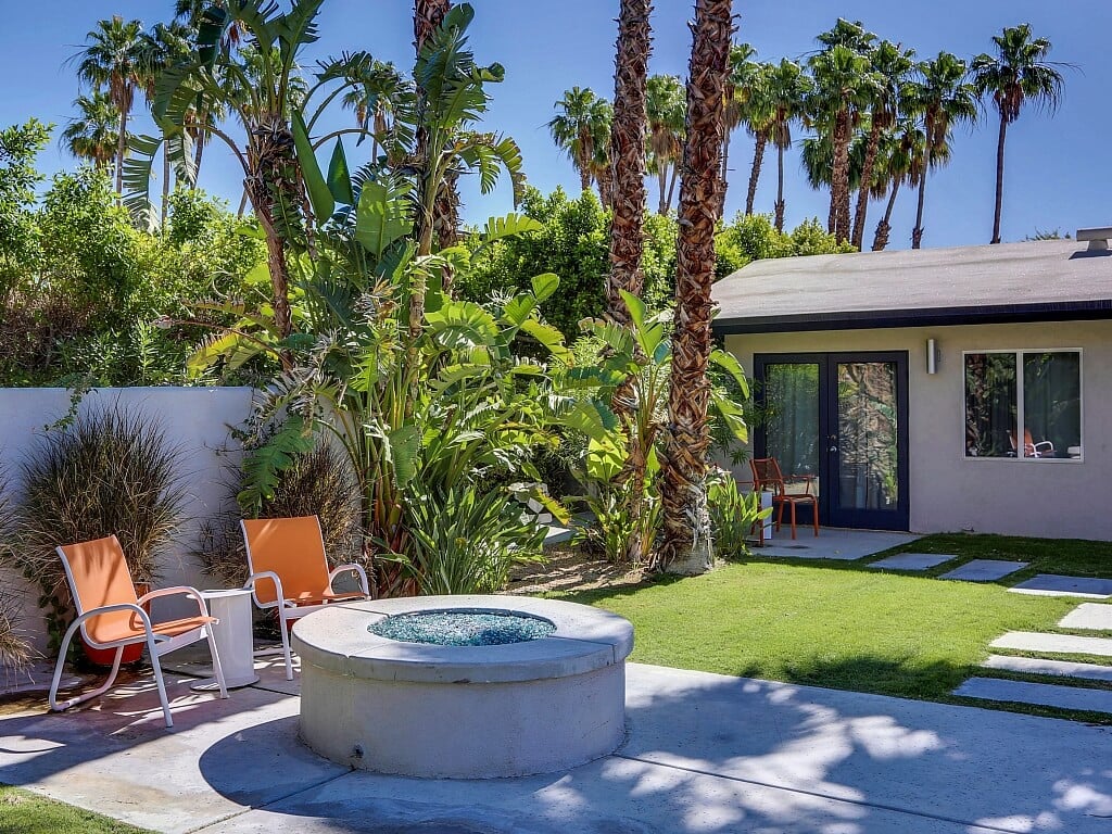 A backyard with a hot tub surrounded by palm trees
