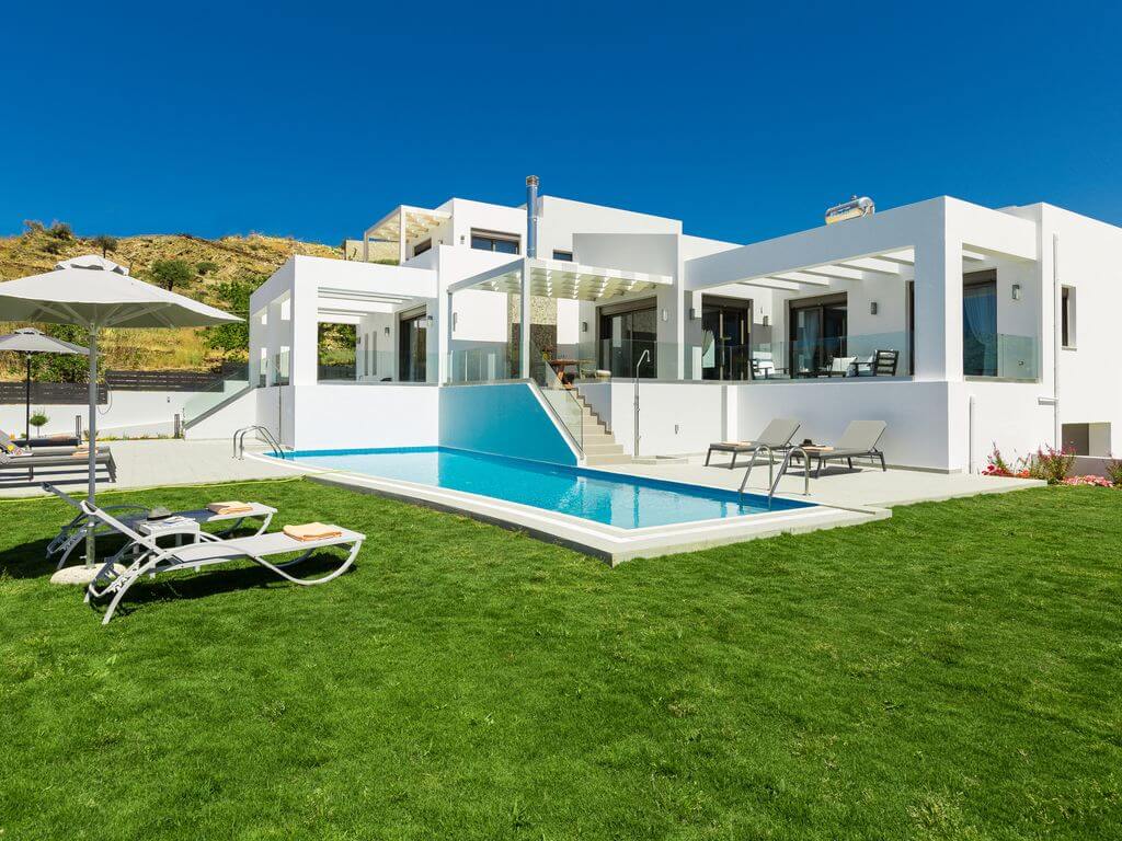 A white house with a pool and lawn chairs
