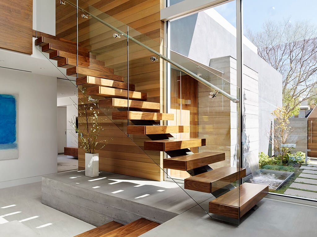 A wooden stair case next to a glass wall

