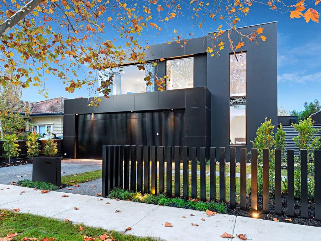 A modern house with a black fence in front of it
