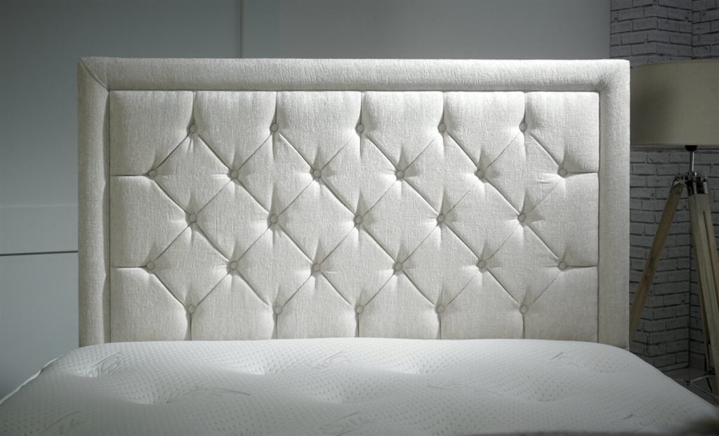 A close up of a bed with a white headboard
