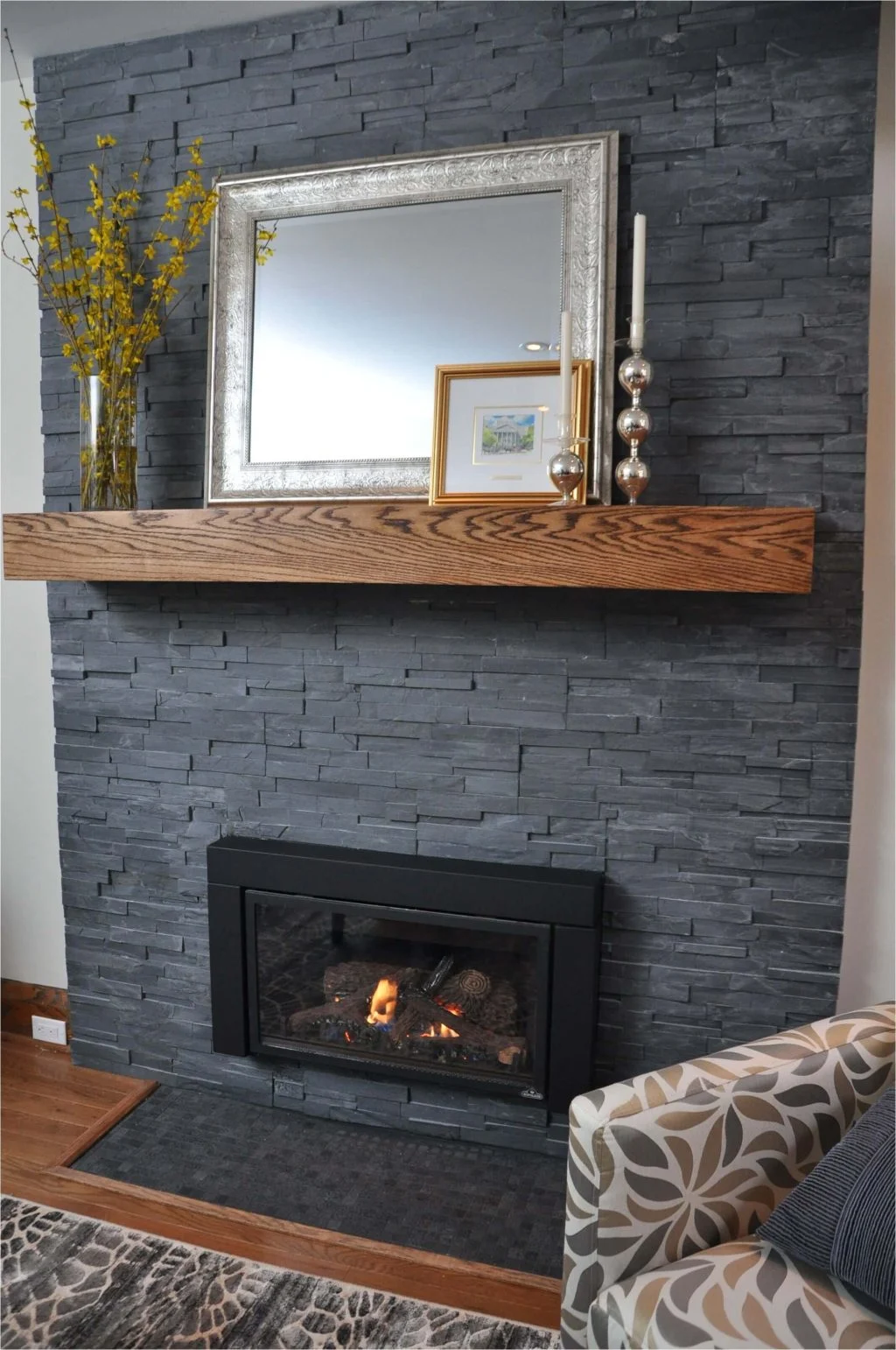 A living room with a grey fireplace and a mirror
