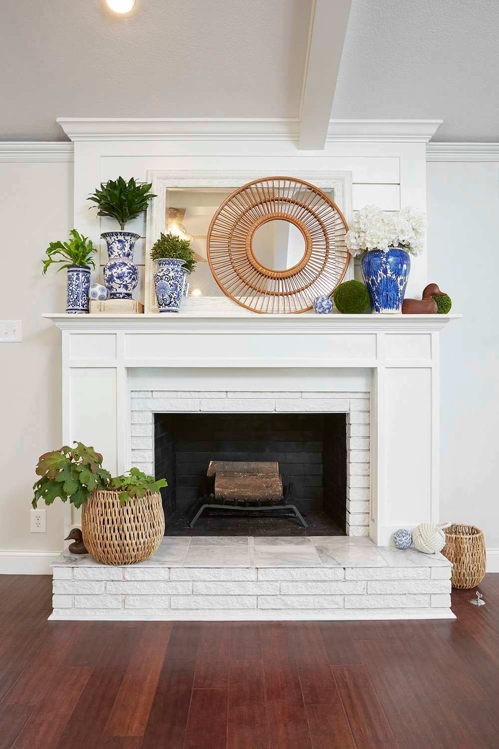 A living room with a white  fire place and potted plants

