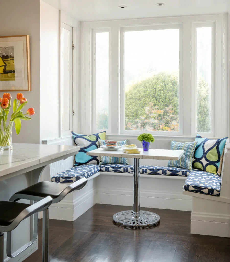 A kitchen with a window seat and a table
