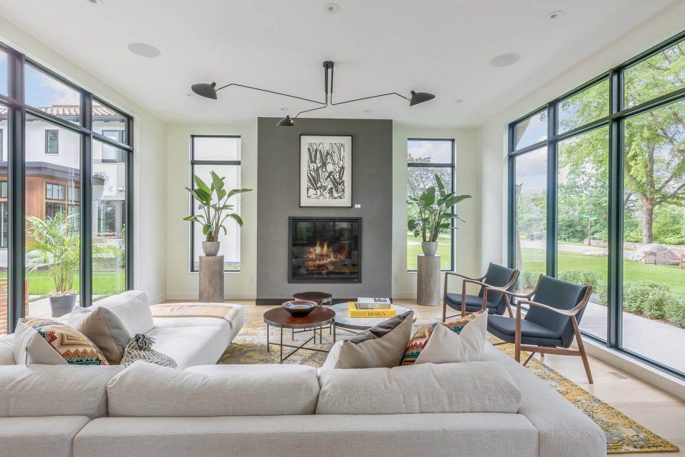 A living room with large windows and a fireplace.