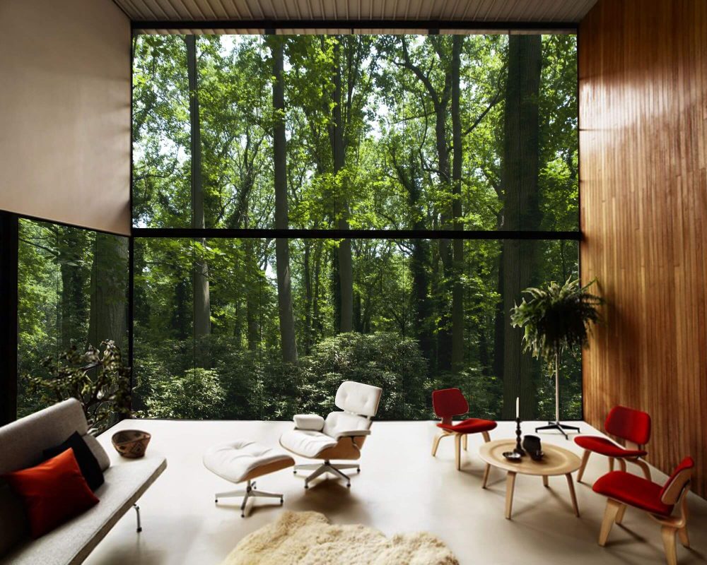 A living room with a large window overlooking a forest.