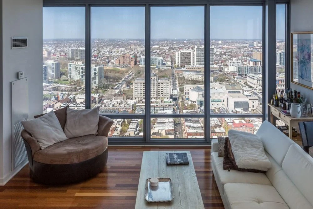 A living room with large windows overlooking a city.
