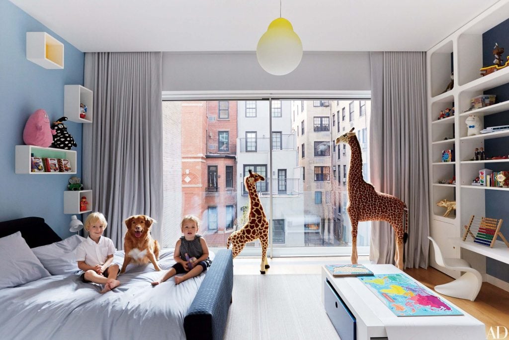 A group of children sitting on a bed in a bedroom
