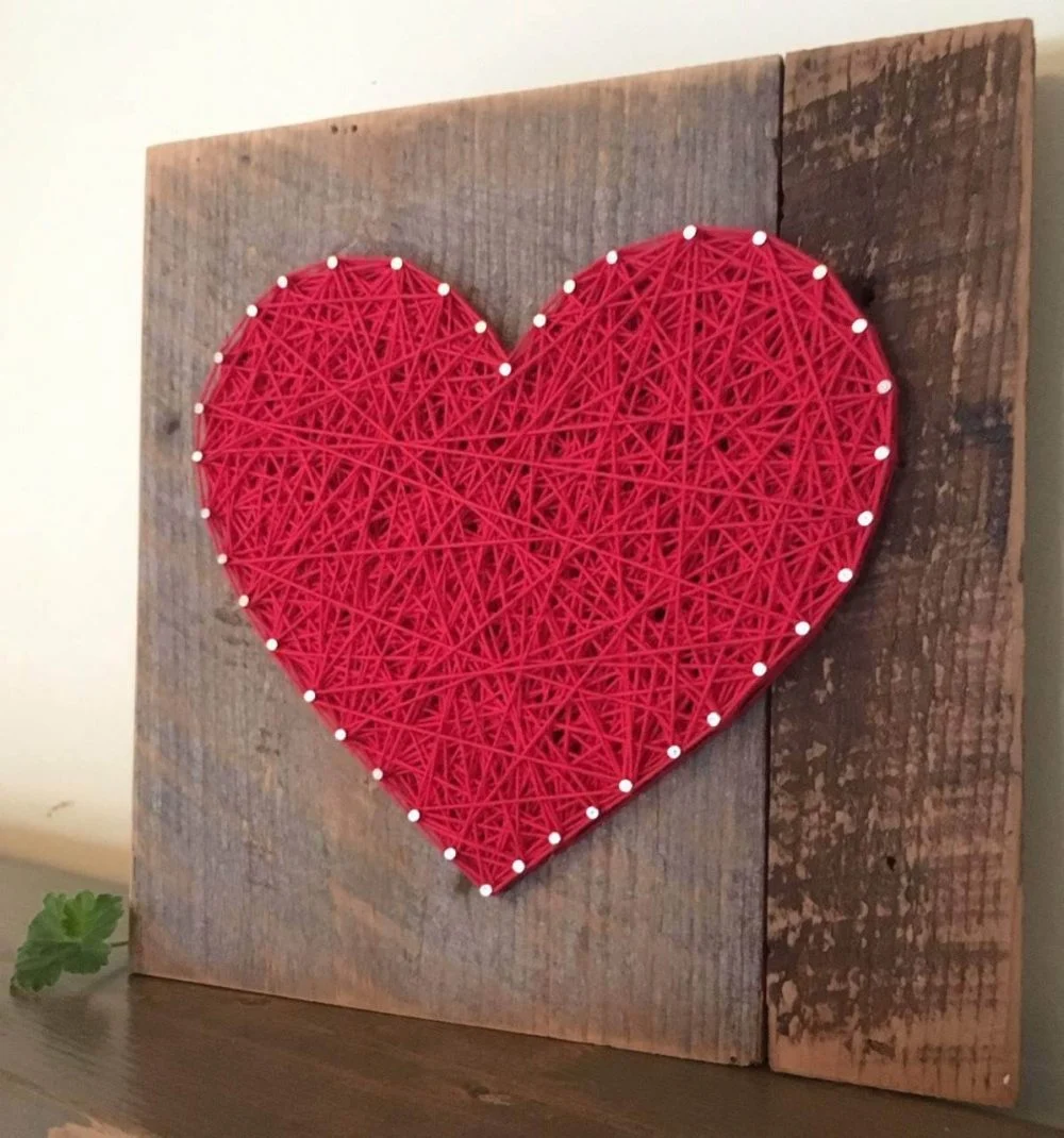 A string art heart on a wooden board
