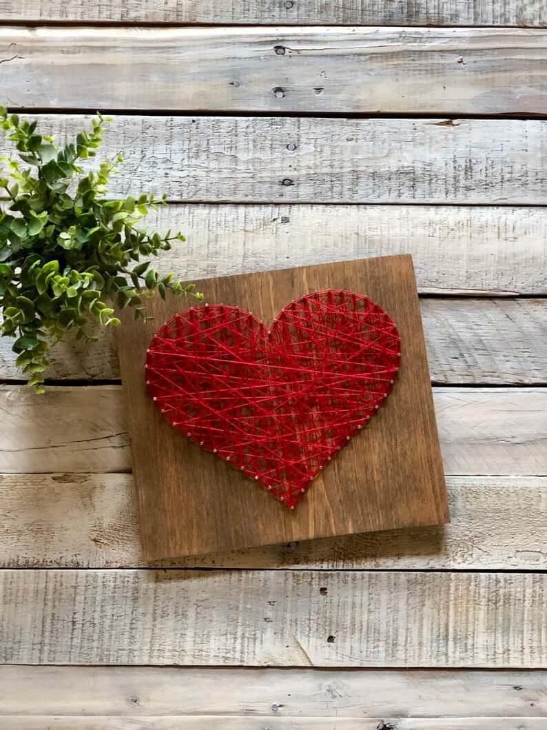 A wooden block with a string heart on it on table
