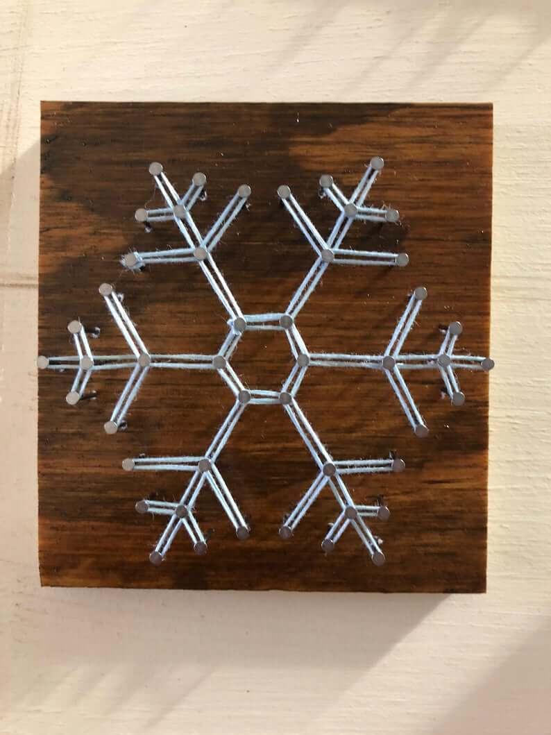A snowflake made out of metal on a wooden board

