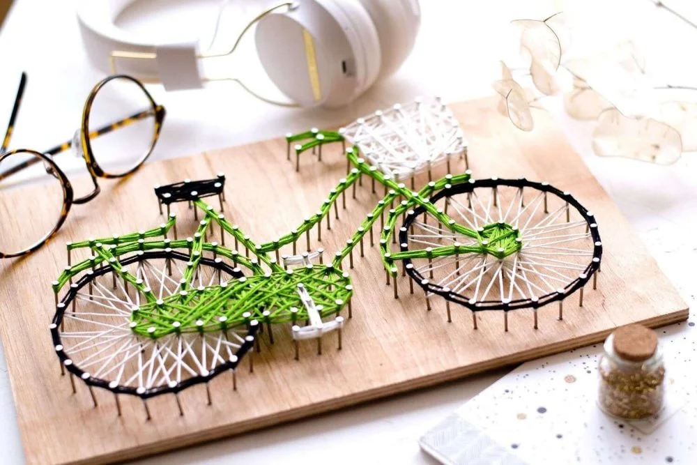 A wooden board with a bike made out of pins
