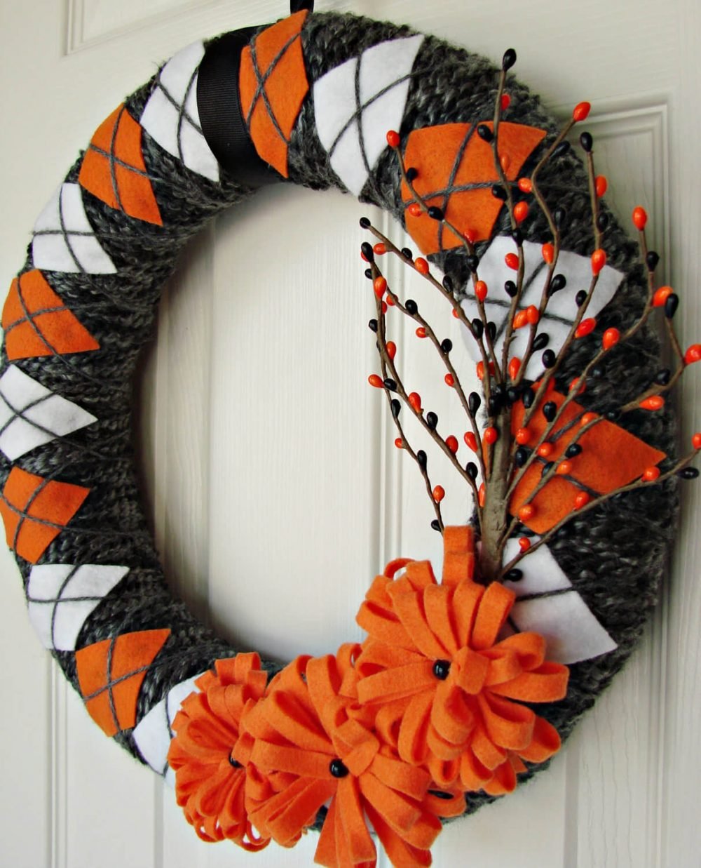 A wreath with orange and white flowers hanging on a door

