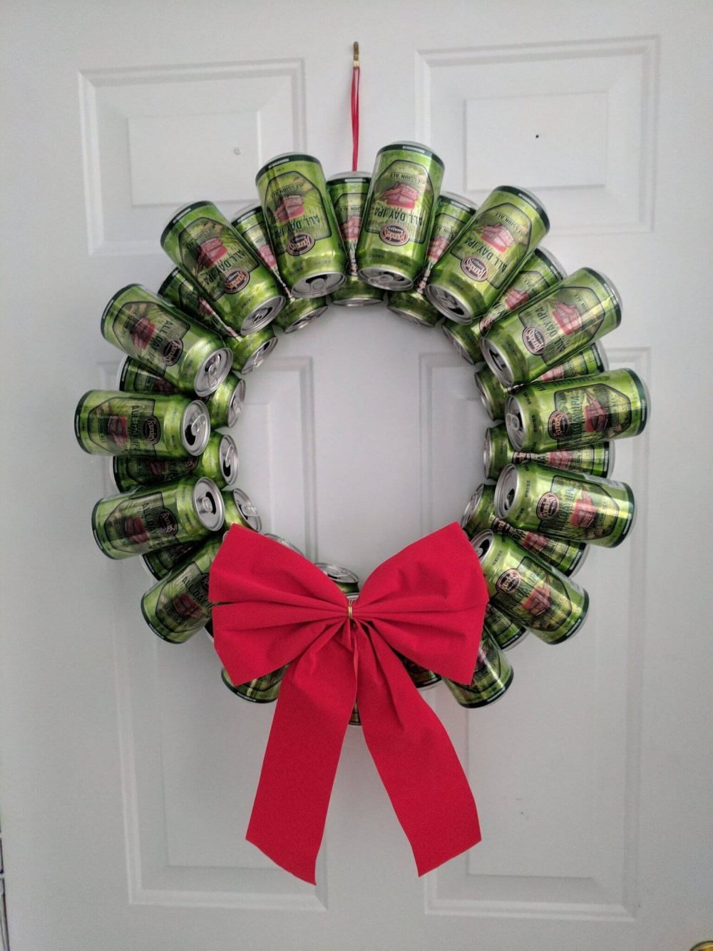 A wreath made out of cans with a red bow
